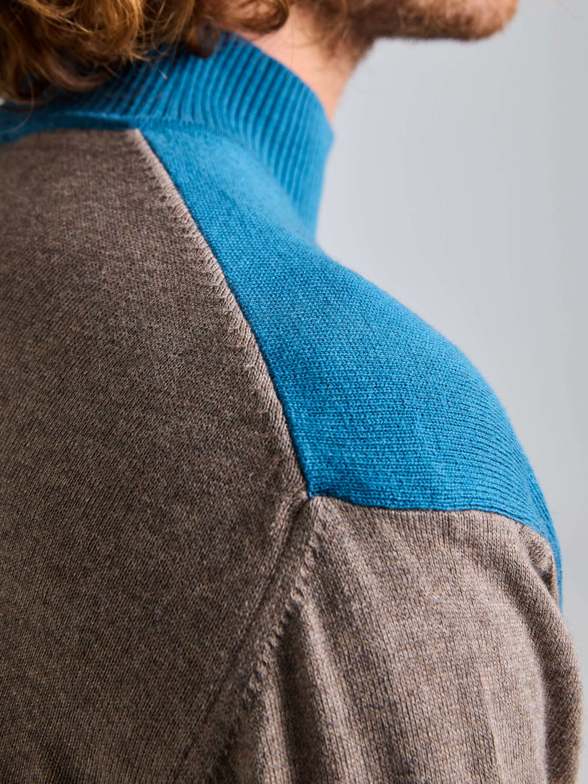 Close-up of the JUMPER ERSE CL by SLAM, highlighting its two-tone design with a brown body complemented by light blue shoulders and collar. This stylish men's jumper stands out against a plain, light-colored background, emphasizing the elegant color transition in the fabric.