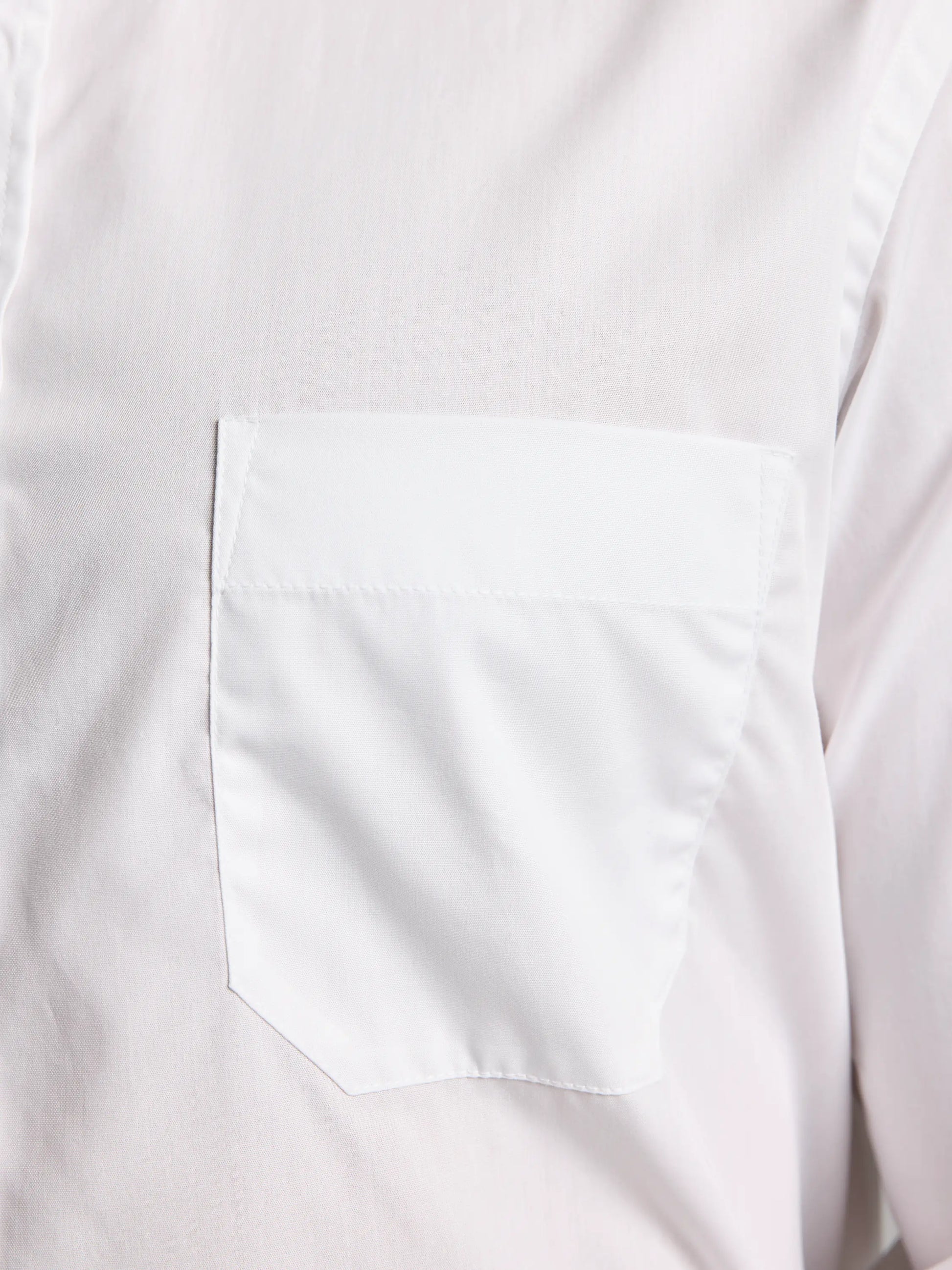 Close-up of the SLAM DECK NO IRON SHIRT CL, a white men's shirt featuring a single chest pocket and an unbuttoned button-down collar. The fabric looks smooth, with the pocket seamlessly integrated into the no iron shirt, highlighting part of the shoulder seam for a flawless finish.