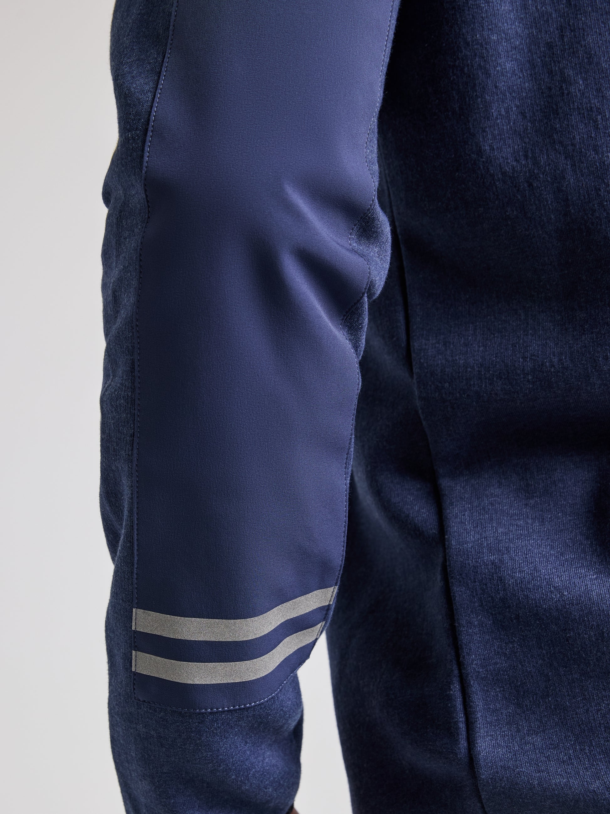 Close-up of a person wearing the navy blue SLAM SWEATSHIRT ANAPO CL with a 4-button opening. The focus is on the left arm, highlighting the dark blue sleeve adorned with two reflective stripes near the elbow. The background is plain and light-colored.