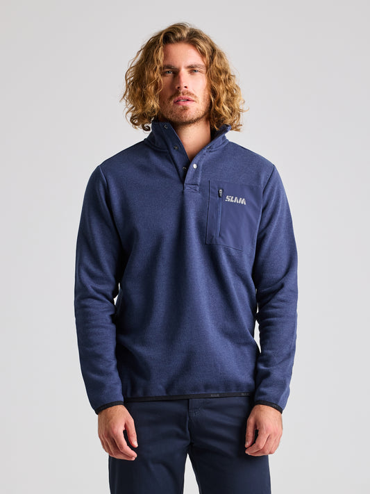 A person with long, wavy hair is wearing the NAVY MELANGE SLAM SWEATSHIRT ANAPO CL, which features a high collar and a chest pocket. The 4-button opening adds a touch of style, while the word "SELLAR" stands out against the fabric. They are standing against a plain light gray background.