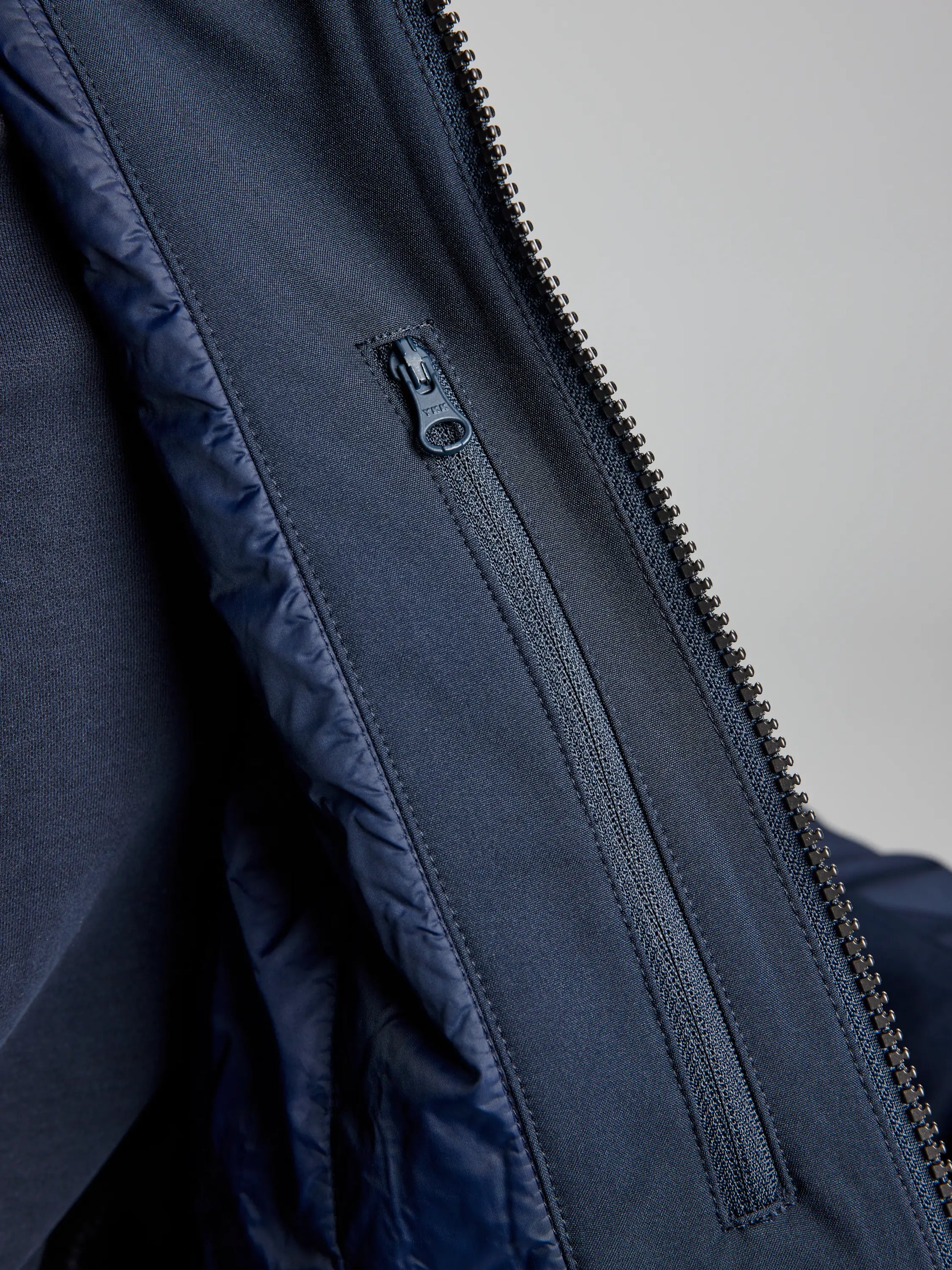 Close-up of the SLAM DOCK INSULATED JACKET CL for men in navy blue, highlighting its waterproof exterior and fleece-lined collar. The interior lining and a zipped pocket are visible, with the metallic zipper partially open to showcase the fabric's texture and stitching detail.