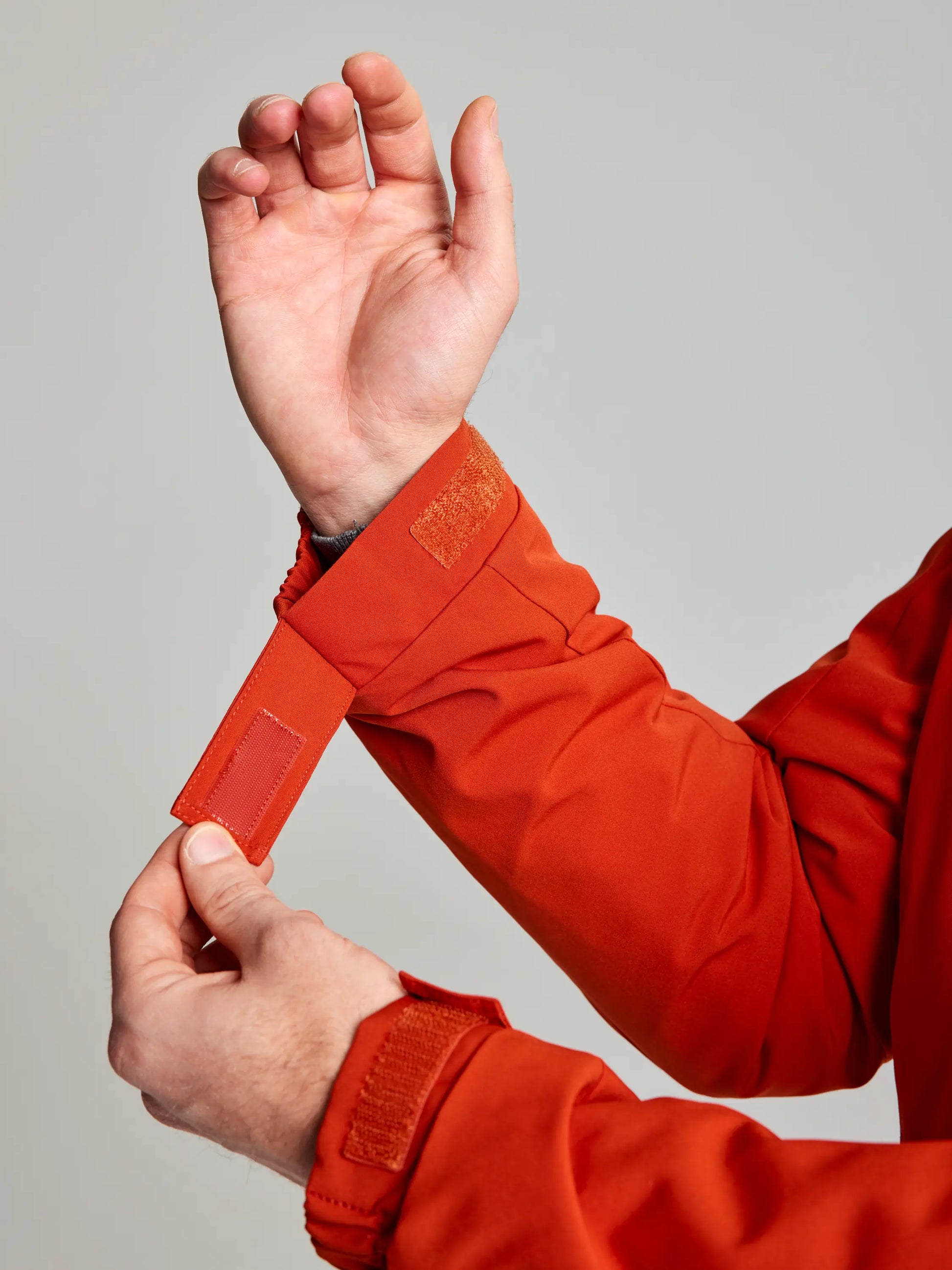 A person wearing a DOCK INSULATED JACKET CL by SLAM adjusts the Velcro strap on the sleeve. The hand is positioned to secure the strap, and the slightly textured fabric complements its fleece-lined collar.